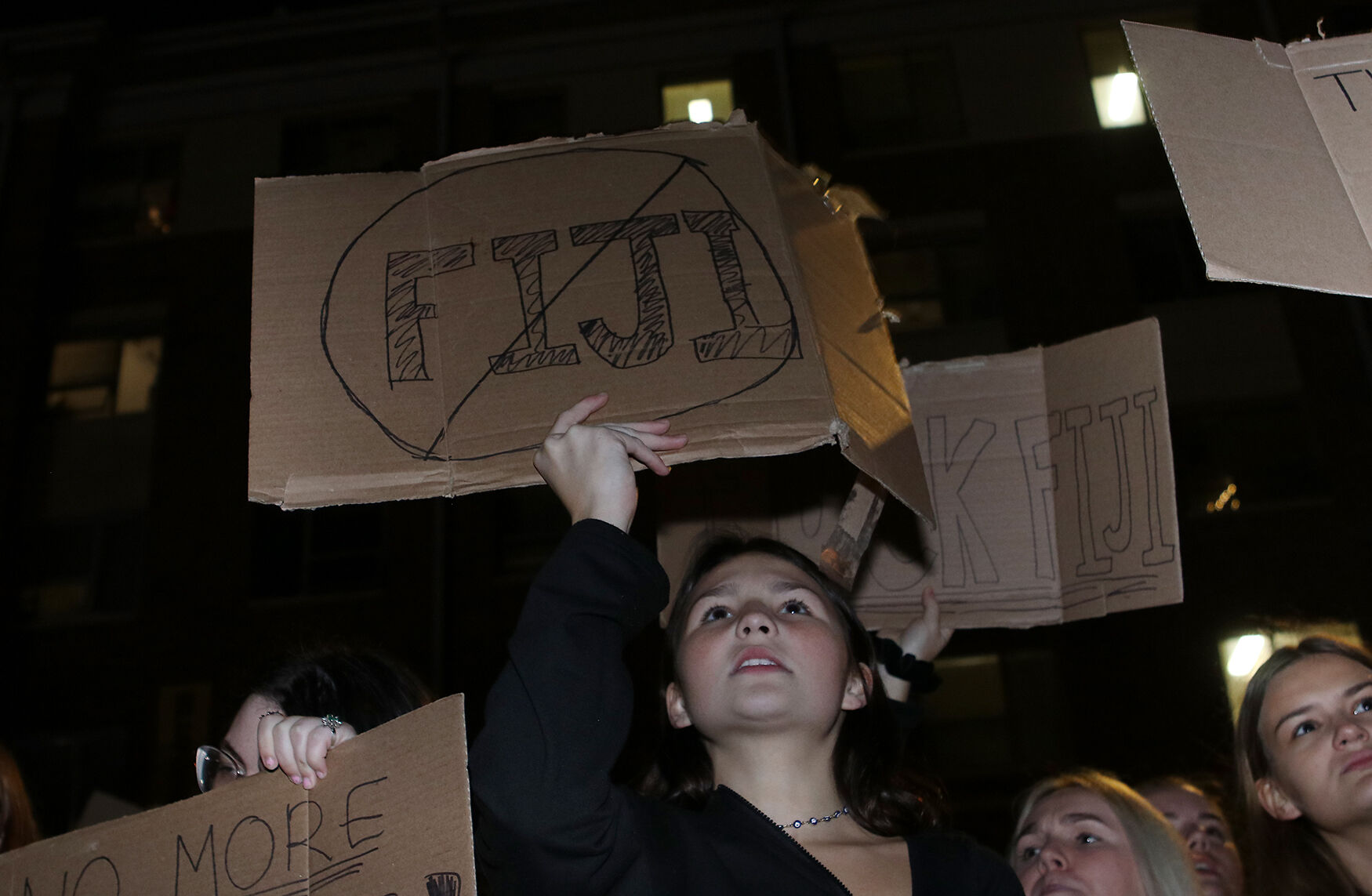 MU junior Eleanor Wilson holds up a sign with a cross through the word “Fiji”